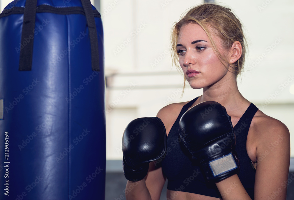 An attractive woman guarding and punching on a sand bag at the gym