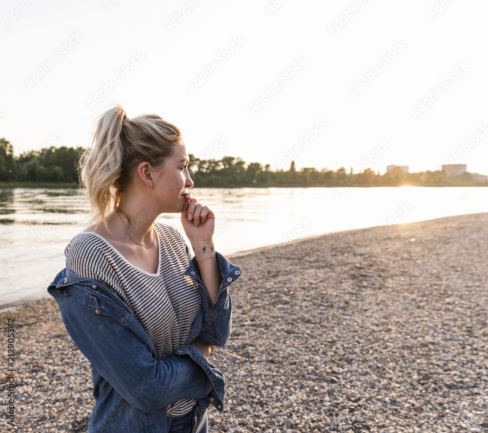 Young blond woman waiting on riverside in the evening
