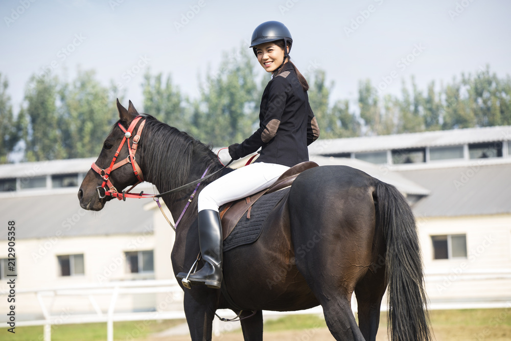 Cheerful young Chinese woman riding horse Cheerful young Chinese woman riding horse