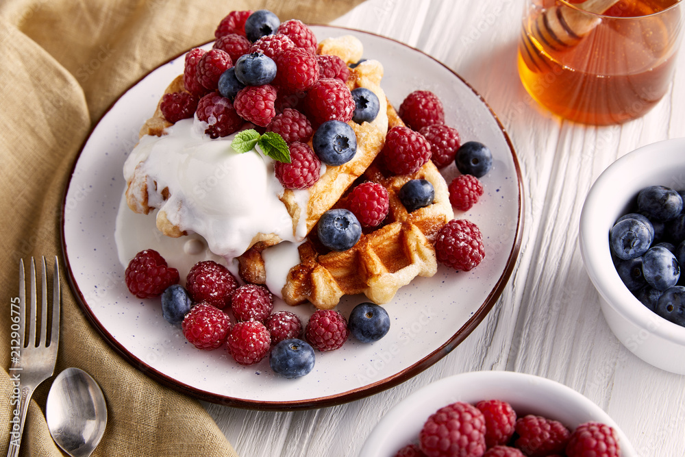 delicious belgian waffles with berries and ice cream on white wooden table