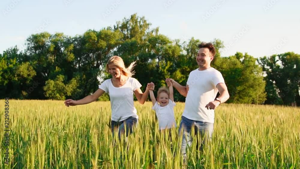 Happy family: Father, mother and son, running in the field dressed in white t-shirts Happy family: Father, mother and son, running in the field dressed in white t-shirts