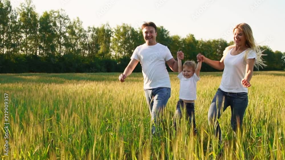 Happy family: Father, mother and son, running in the field dressed in white t-shirts Happy family: Father, mother and son, running in the field dressed in white t-shirts