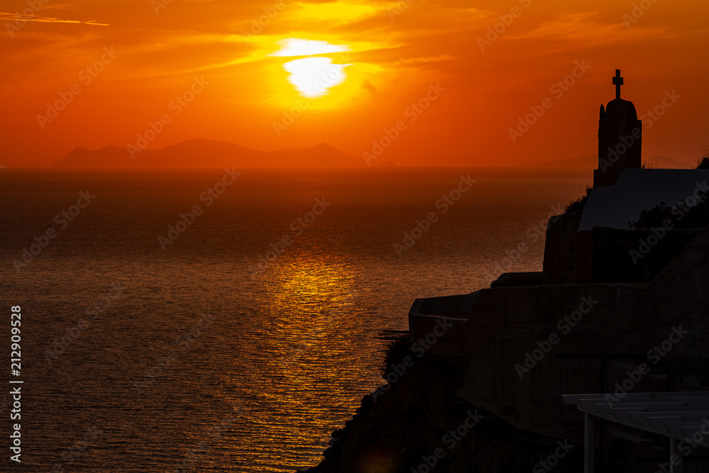 Beautiful sunset with silhouette of chapel on the cliff in Oia Santorini Greece