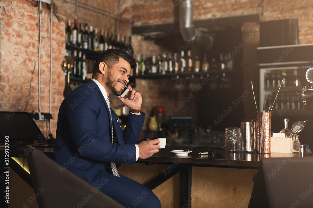 Cheerful business talking on phone in bar
