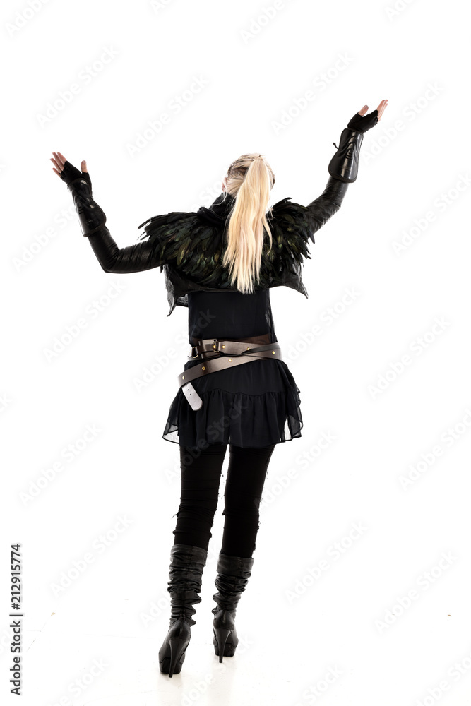 full length portrait of blonde girl wearing lack fantasy warrior outfit. standing pose wit bak to the camera. isolated on white studio background. full length portrait of blonde girl wearing lack fantasy warrior outfit. standing pose wit bak to the camera. isolated on white studio background.