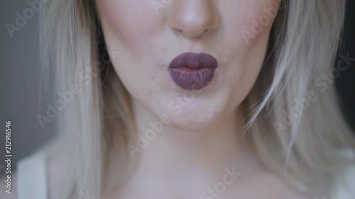 Women's lips are colored with dark lipstick. Kiss close-up