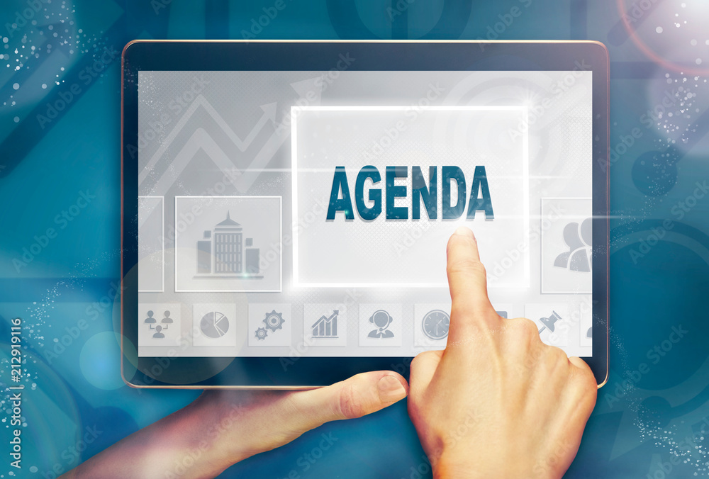 A hand holiding a computer tablet and pressing a agenda business concept.
