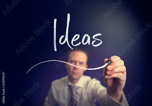 A businessman writing a ideas concept with a white pen on a clear screen.