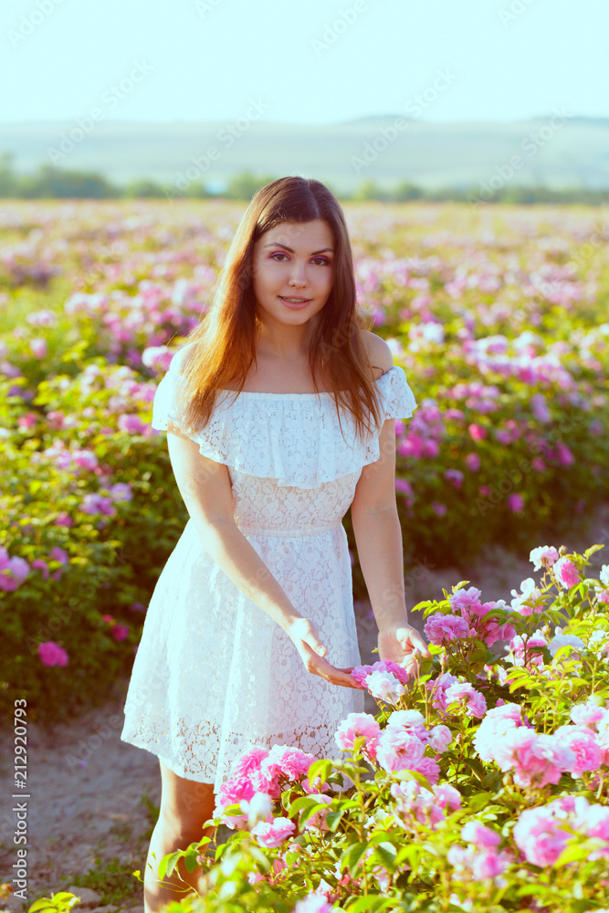 Beautiful young woman posing near roses in a garden. Beautiful young woman posing near roses in a garden.