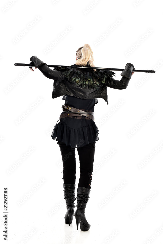 full length portrait of blonde girl wearing lack fantasy warrior outfit. standing pose wit bak to the camera. isolated on white studio background. full length portrait of blonde girl wearing lack fantasy warrior outfit. standing pose wit bak to the camera. isolated on white studio background.
