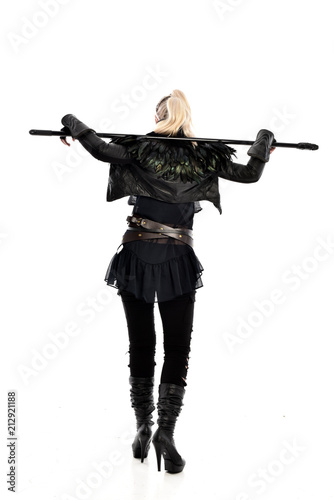 full length portrait of blonde girl wearing lack fantasy warrior outfit. standing pose wit bak to the camera. isolated on white studio background.