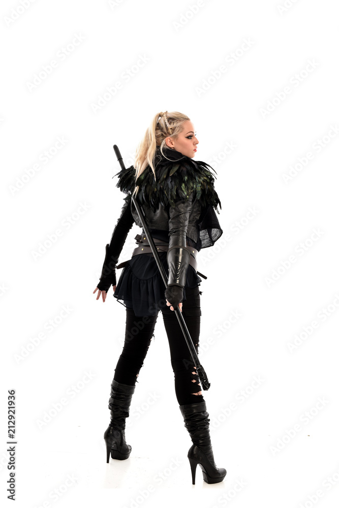 full length portrait of blonde girl wearing lack fantasy warrior outfit. standing pose wit bak to the camera. isolated on white studio background. full length portrait of blonde girl wearing lack fantasy warrior outfit. standing pose wit bak to the camera. isolated on white studio background.