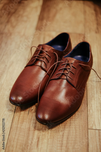 Brown wedding shoes of a groom on wooden floor background