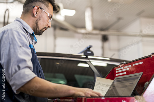 Handsome mechanic job in uniform working on car