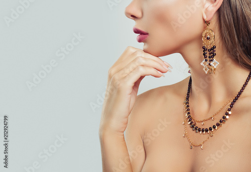 Gold jewelry on woman neck closeup. Necklace and Earrings on female body on background with copy space