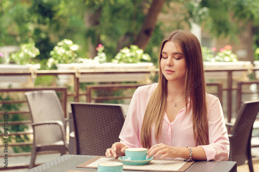 Young woman drinking coffee in a cafe outdoors