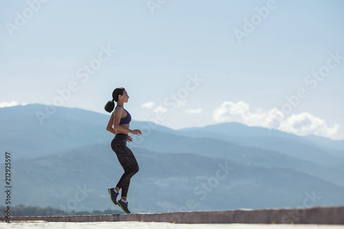 The girl goes in for sports, runs in the morning along the promenade by the sea, against the mountains.