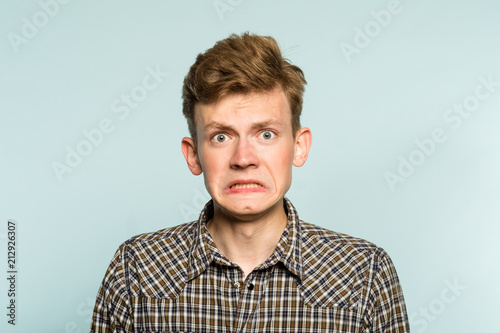 awkward gawky fumbling oafish dorky man facial expression. portrait of a young guy on light background. emotion facial expression. feelings and people reaction.
