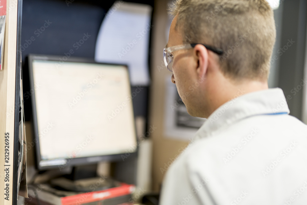 Professional car mechanic working in auto repair service using computer