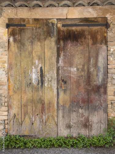 very old weathered brown doors in ancient wall of medieval village in french provence
