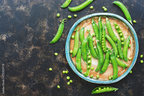 Fototapeta Naklejka Na Ścianę i Meble -  Green peas in a ceramic rustic plate on a dark background. Flat lay,copy space.