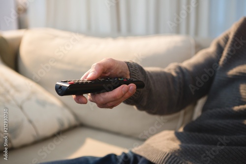 Man changing channel with remote control at home photo