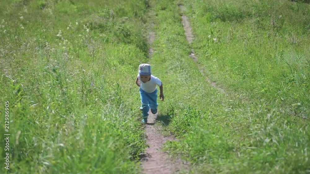 A little boy runs along a narrow path in the forest. Outdoor entertainment. Hot summer day A little boy runs along a narrow path in the forest. Outdoor entertainment. Hot summer day