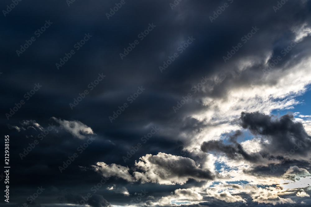 Dramatic dark rain clouds with a blue sky gap.