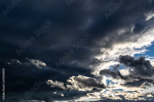 Dramatic dark rain clouds with a blue sky gap.