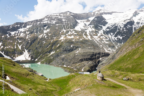 Solitary chapel near the emerald green Margaritze stausee lake on the Grossglockner High Alpine Road. photo