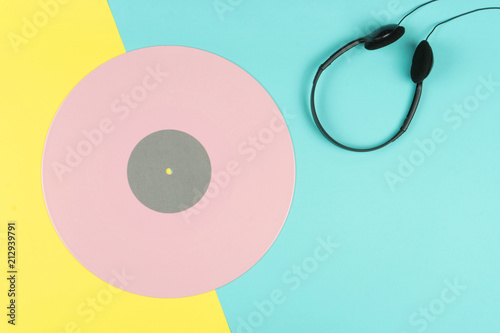 top view of a pink long play vinyl record or LP with a black on-ear headphone on the yellow and blue background photo