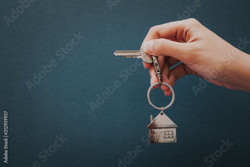 Woman's hand holding house key with house shape key chain.