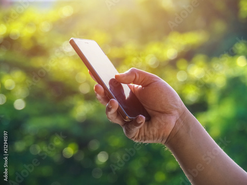 Close up of a man's hand using mobile smart phone outside on sunny summer day