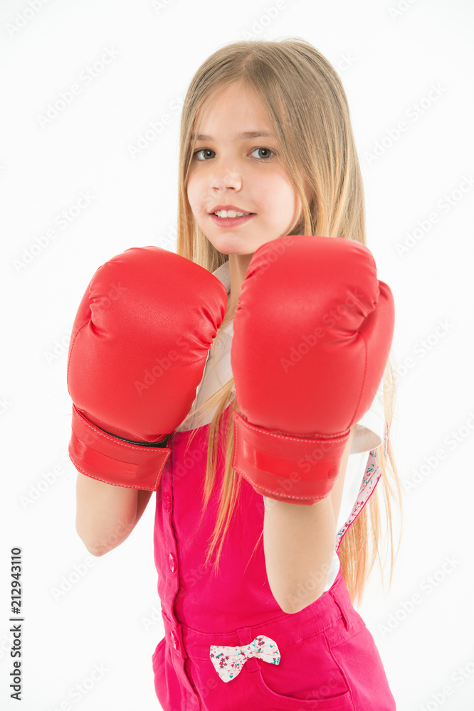Little fighter before combat. Girl with long blond hair wearing huge red boxing gloves, sport concept. Kid in pink overalls isolated on white background. Brave girl ready to protect herself Little fighter before combat. Girl with long blond hair wearing huge red boxing gloves, sport concept. Kid in pink overalls isolated on white background. Brave girl ready to protect herself