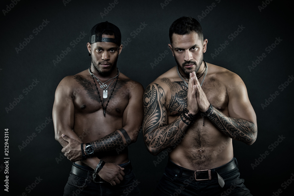 Sportsmen with sexy fit torsos. Martial arts contestants calming down before fight. Bodybuilders isolated on black background. Hispanic man with geometrical tattoos holding hands in prayer gesture
