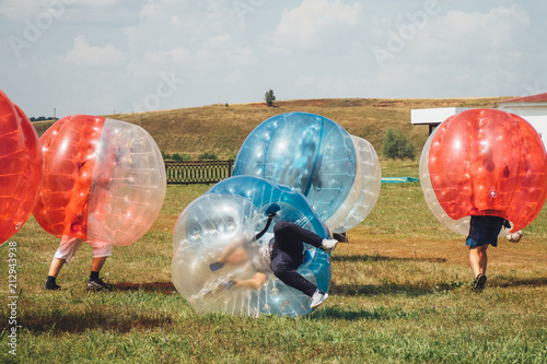 People play bumperball zorbsoccer outdoor. summer time
