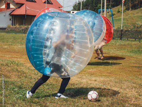 People play bumperball zorbsoccer outdoor. summer time