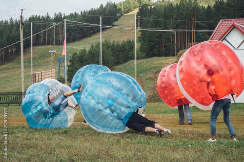People play bumperball zorbsoccer outdoor. summer time