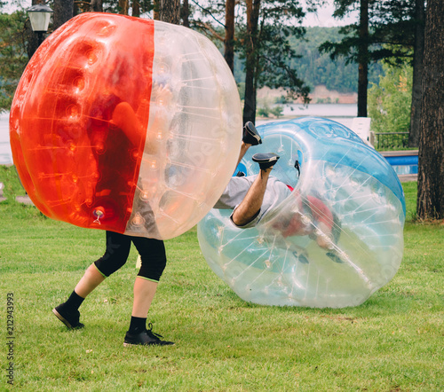 People play bumperball zorbsoccer outdoor. summer time