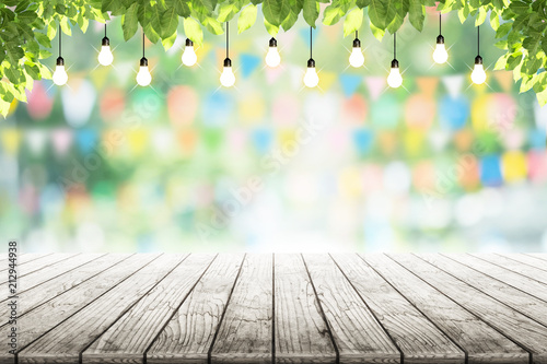 Empty wooden table and bulbs within party in garden background blurred.