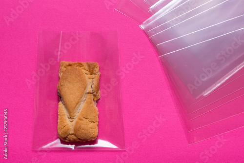 Fotografi biscuit in cellophane bag on pink background