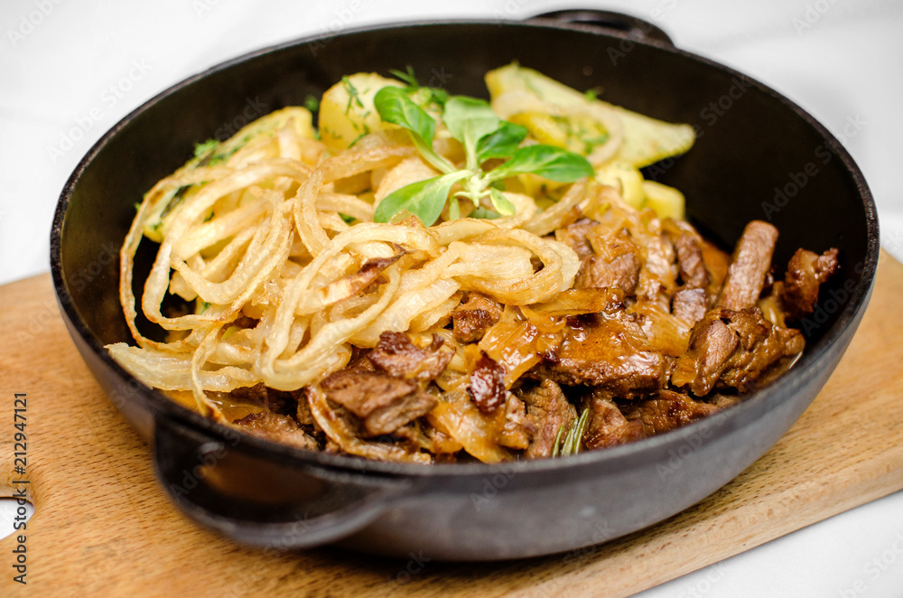 Lunch from roasted meat of varnish and potatoes in a black frying pan on a wooden kitchen board Lunch from roasted meat of varnish and potatoes in a black frying pan on a wooden kitchen board
