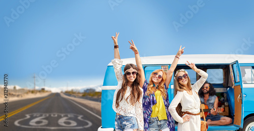 road trip, travel and people concept - happy young hippie friends having fun and dancing at minivan car over us route 66 background