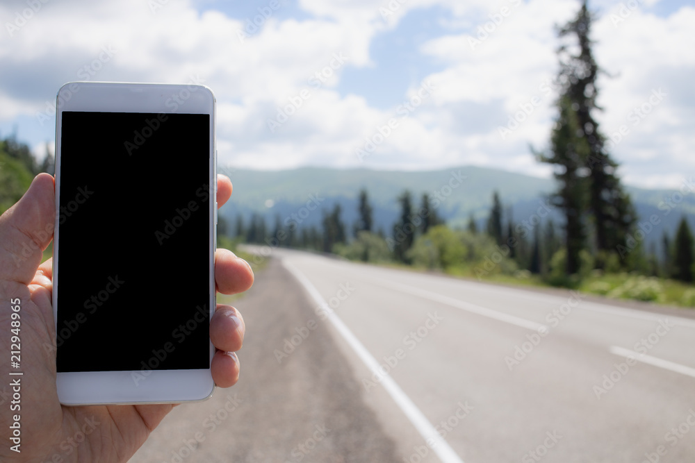 Mockup image of a man using smart phone with blank black screen on road