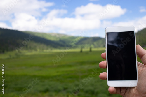 The traveler uses a smart phone in the mountains