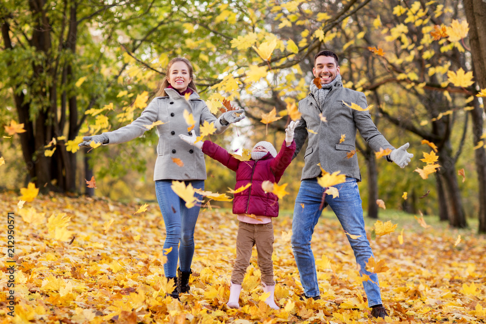 family, season and people concept - happy mother, father and little daughter playing with autumn leaves at park