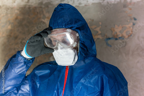 A man in blue protective suit, glasses and respirator