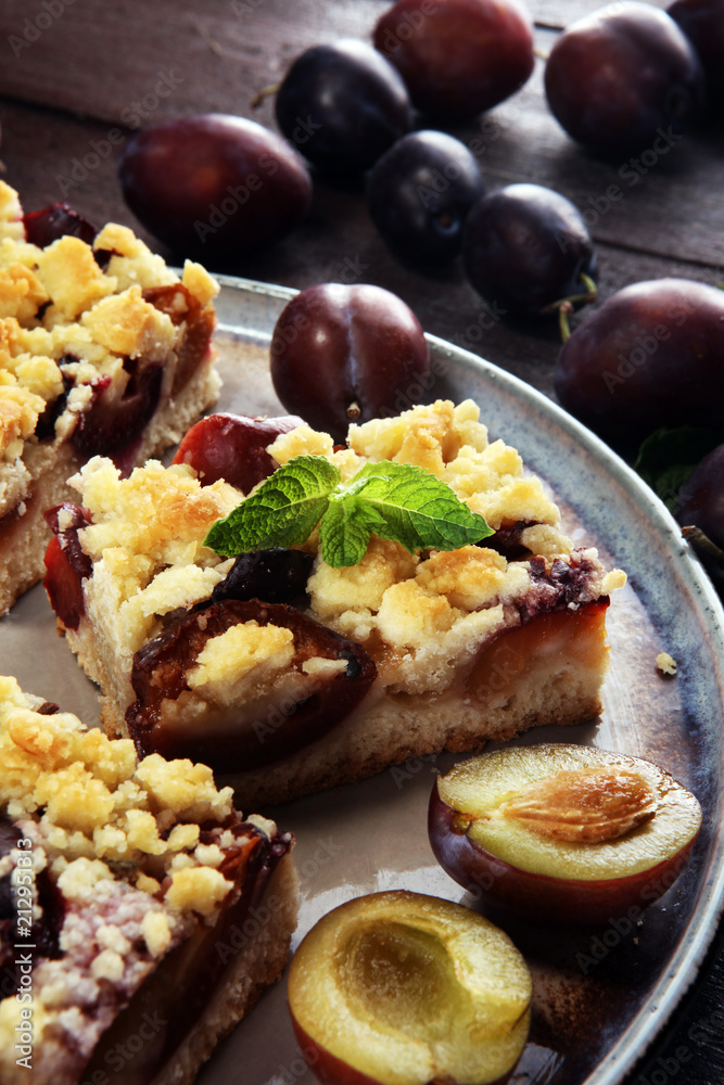 Rustic plum cake on wooden background with plums around. Rustic plum cake on wooden background with plums around.