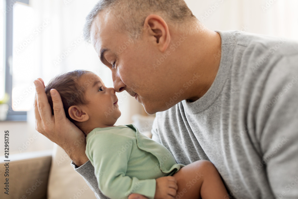 family, fatherhood and people concept - happy father with little baby boy sitting on sofa at home