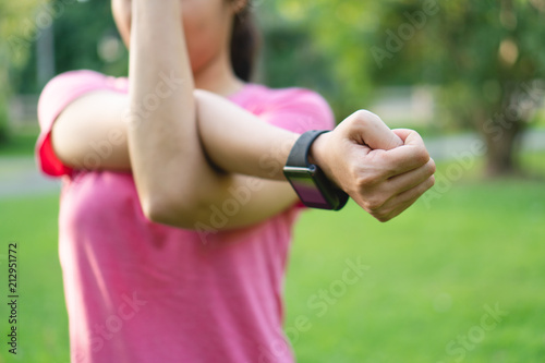 Young asian woman stretching arms before fitness training session at park.